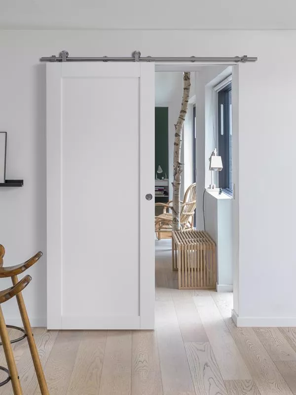 En vit skjutdörr med en modern design och en diskret metallisk skena upptill.
